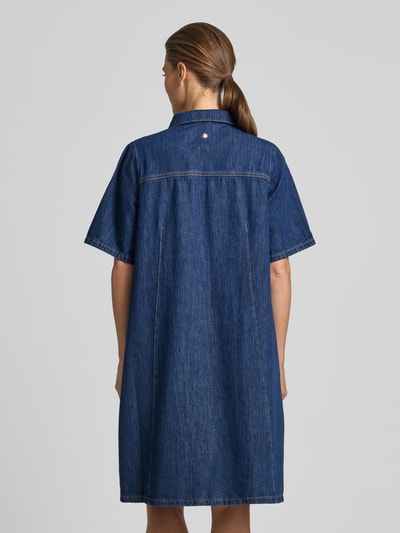 Frauenmodel trägt Knielanges Jeanskleid mit Brusttaschen Modell 'Biba East' von MOS MOSH aus Reine Baumwolle in klassischem Blau, Straight Fit, Kentkragen, kurze Knopfleiste, Knielänge, Ganzkörperansicht Rückansicht.