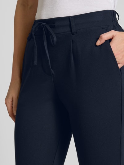 Frauenmodel trägt Easy Pants mit Bundfalten von TOM TAILOR in Dunkelblau, Viskosemischung mit Stretch-Anteil, Nahaufnahme Oberkörper.