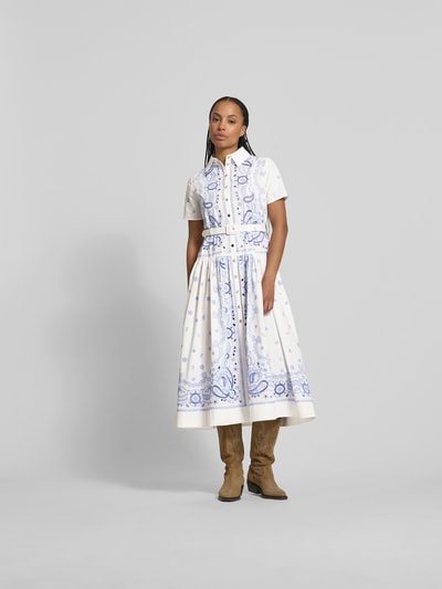 Frauenmodel trägt Hemdblusenkleid in Midilänge von Self-Portrait aus weißer Baumwolle mit blauen Paisley-Stickereien, taillierte Passform, Taillengürtel mit Dornschließe, Midilänge, Ganzkörperansicht von vorne.