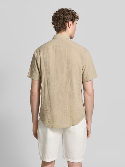 Mężczyznamodel nosi Relaxed Fit Freizeithemd mit Logo-Stitching und Kentkragen od Lerros, seersucker, krój relaxed fit, kołnierzyk typu kent, listwa guzikowa, wyhaftowane logo, zaokrąglony dół, długość tyłu w rozmiarze M: 75 cm, szerokość w rozmiarze M: 45 cm, długość rękawów w rozmiarze M: 25 cm, beżowa faktura i jasne spodenki, tekstura marszczona, jasne kolory, widok całej sylwetki od tyłu