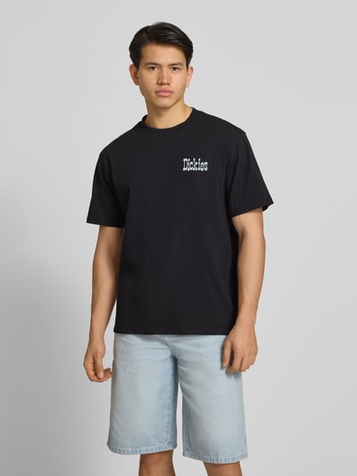 Männermodel trägt Herren T-Shirt mit Logo Modell 'VERNAL' von Dickies in Schwarz, Reine Baumwolle, Relaxed-Fit, Rundhalsausschnitt, Ganzkörperansicht von vorne.