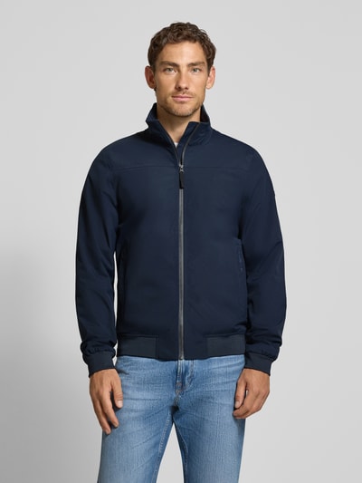 Männermodel trägt Regular Fit Jacke mit Stehkragen Modell 'Alvin' von Didriksons in Dunkelblau, Reißverschluss, Ganzkörperansicht von vorne.