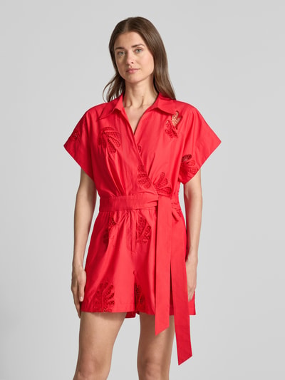 Frauenmodel trägt roten Jumpsuit in Wickel-Optik Modell 'TRACY' von SUNCOO PARIS aus Reine Baumwolle mit Lochstickerei, Relaxed-Fit, Bindegürtel, Hemdblusenkragen, Nahaufnahme Oberkörper.