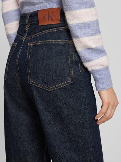 Frauenmodel trägt Straight Fit Jeans mit Label-Detail von Calvin Klein Jeans, dunkle Reine Baumwolle, Modell THE STRAIGHT BOOT RESIN, Detailaufnahme Rückansicht.