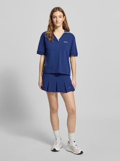 Frauenmodel trägt Poloshirt mit Label-Stitching von adidas Sportswear in Blau, reine Baumwolle, lockerer Schnitt, Ganzkörperansicht von vorne.