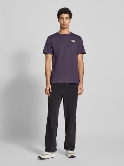 Männermodel trägt Regular Fit T-Shirt aus Baumwoll-Mix Modell 'EVOLUTION' von The North Face in Dunkellila mit Label-Detail, Ganzkörperansicht von vorne. Herren T-Shirt, Rundhalsausschnitt, Rückenlänge bei Größe M 70 cm.