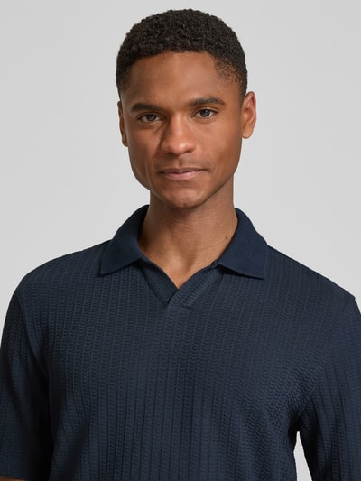 Männermodel trägt Slim Fit Poloshirt mit Strukturmuster und V-Ausschnitt von bugatti aus Reine Baumwolle in Dunkelblau, Nahaufnahme Oberkörper. Rückenlänge bei Größe M: 70 cm.