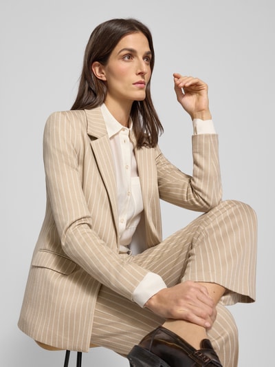 Frauenmodel trägt Blazer mit Reverskragen von Comma im Material-Mix mit Viskose-Anteil, lockerer Schnitt, Beige mit weißen Streifen, Knopfverschluss, Pattentaschen, Nahaufnahme Oberkörper.