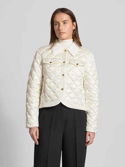 Kobiece model prezentuje Regular Fit Jacke in Stepp-Optik mit Umlegekragen od Marc Cain w kolorze kremowym, widok z przodu, całej sylwetki. Kurtka z przeszyciami, kieszeniami na piersi, kieszeniami bocznymi i złotymi guzikami, długość tyłu 53 cm, szerokość ramion 45 cm, szerokość biustu 51 cm, długość rękawa 60 cm.