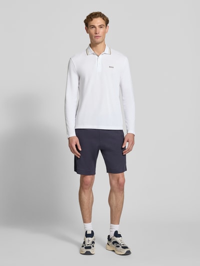 Männermodel trägt Regular Fit Poloshirt aus reiner Baumwolle Modell 'Plisy' von BOSS, weiße Farbe, glatte Textur, Ganzkörperansicht von vorne, Herren Poloshirt von BOSS.