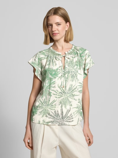 Frauenmodel trägt Loose Fit Bluse aus reiner Viskose von s.Oliver BLACK LABEL, Optik:Allover-Muster, Passform: Loose-Fit, V-Ausschnitt, Muster: Botanic, Smok-Details, Verschluss: Bindeband, Ärmelform: Kurzarm, Material: Viskose, grün-weiß, Ganzkörperansicht von vorne.