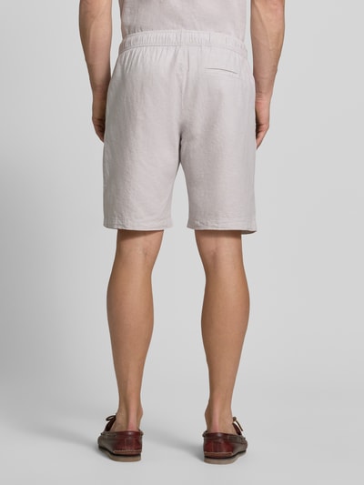 Männermodel trägt Shorts aus Leinen-Baumwoll-Mix mit elastischem Bund von MCNEAL in hellem Beige, Regular-Fit, Ganzkörperansicht Rückansicht. Kontext: Herren Shorts, Tunnelzug, Bundweite bei Größe M 44 cm, Innenbeinlänge bei Größe M 23 cm.