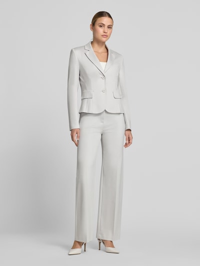 Frauenmodel trägt Slim Fit Blazer mit Pattentaschen von Marc Cain im hellen Material-Mix mit Reverskragen und Knopfverschluss, Ganzkörperansicht von vorne. Rückenlänge 54 cm, Brustweite 35 cm, Ärmellänge 63 cm, Größe 36.