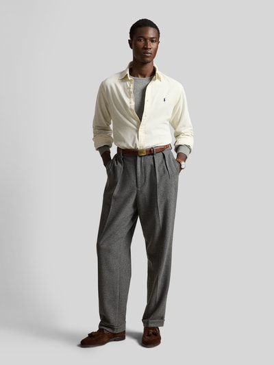 Männermodel trägt Custom Fit Freizeithemd aus reiner Baumwolle von Polo Ralph Lauren in Creme, kombiniert mit grauer Stoffhose, Ganzkörperansicht von vorne. Herren Freizeithemd von Polo Ralph Lauren.