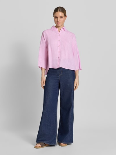 Frauenmodel trägt Leinenbluse mit überschnittenen Schultern von Christian Berg Woman in Rosa, aus reinem Leinen, loose Fit, Kentkragen, Knopfleiste, 3/4-Arm zu weiter Jeans, glatte Textur; Ganzkörperansicht von vorne.