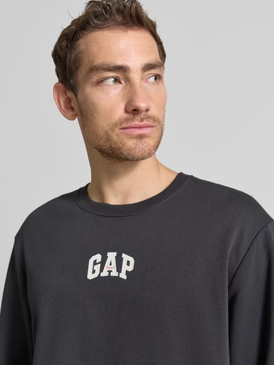 Männermodel trägt T-Shirt mit Rundhalsausschnitt und Logo-Print van GAP in katoenmix, loose fit, ribboorden, logoprint, Nahaufnahme Oberkörper.