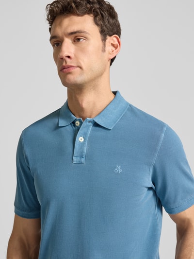 Männermodel trägt Poloshirt aus Baumwolle von MARC O’POLO DENIM in Blau, Piqué mit Logo, Polokragen, Knopfleiste, Nahaufnahme Oberkörper.