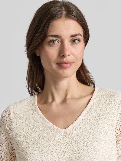 Frauenmodel trägt Regular Fit T-Shirt in Heckel-Optik Modell 'MAYA' von Vero Moda, Optik:Unifarben, Passform:Regular-Fit, Optik:Allover-Muster, Ausschnitt:V-Ausschnitt, Ärmelform:Kurzarm, cremefarbene Struktur mit feinem Muster, Nahaufnahme Oberkörper.