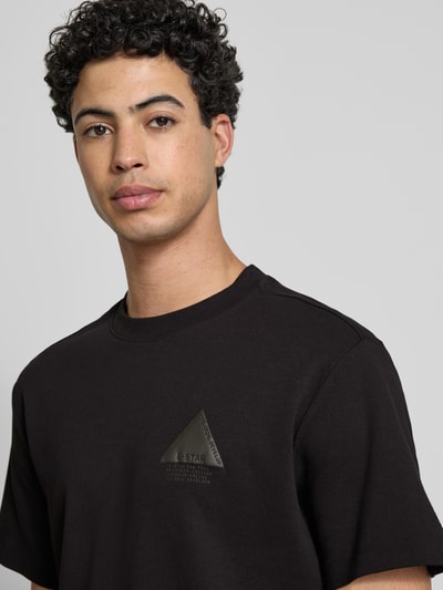 Männermodel trägt Regular Fit T-Shirt mit Logo-Detail von G-Star Raw aus reiner Baumwolle, schwarzer Stoff, Nahaufnahme Oberkörper.