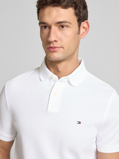 Männermodel trägt Regular Fit Poloshirt mit Logo-Stitching von Tommy Hilfiger, bawełna z elastanem, kolor biały, zbliżenie na górę ciała.