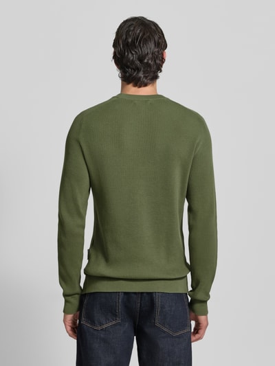 Männermodel trägt Slim Fit Pullover in Strick-Optik Modell 'Nordin' von Casual Friday in Olivgrün, reine Baumwolle, Ganzkörperansicht Rückansicht.