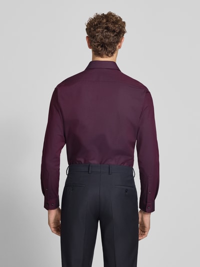 Männermodel trägt Regular Fit Business-Hemd mit Kentkragen von Christian Berg Men, bordeaux, glatte Textur, Ganzkörperansicht Rückansicht. Baumwoll-Mix mit Stretch-Anteil, abgerundeter Saum.