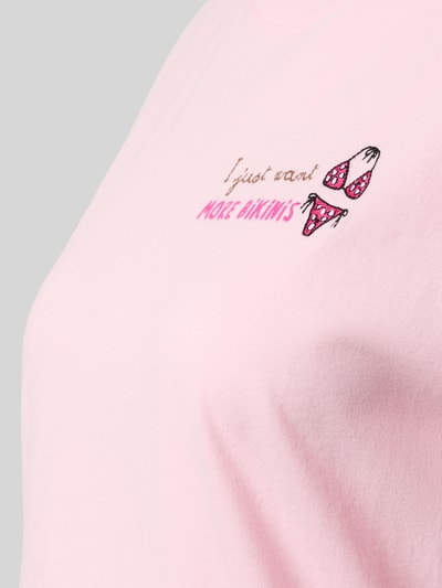 Frauenmodel trägt Damen T-Shirt mit Rundhalsausschnitt aus Reiner Baumwolle, Motiv- und Statement-Stitching, Modell 'EMILIE' von MC2 Saint Barth in zartem Rosaton, Textur weich, Nahaufnahme Oberkörper.