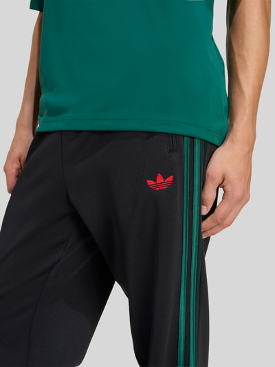 Männermodel trägt Regular Fit Sweatpants mit katoen van adidas Originals, look: effen kleuren, pasvorm: regular fit, logostitching, galonstrepen, boord: elastisch, materiaalverwerking: sweat, detailaufnahme bovenbeen