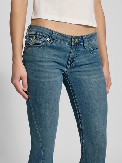Vrouwenmodel draagt Low Rise Flared Jeans met steekzakken model 'JOEY' van TRUE RELIGION in blauwe used-look, katoenmix met stretch, detailopname heup en bovenbenen.