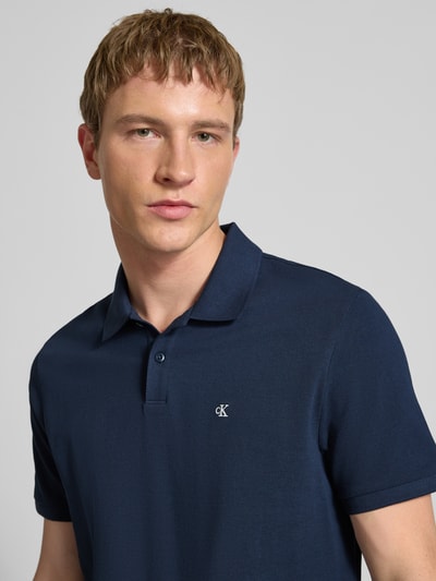 Männermodel trägt Straight Fit Poloshirt mit Label-Stitching von Calvin Klein Jeans aus reiner Baumwolle, Nahaufnahme Oberkörper.