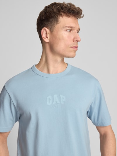 Männermodel trägt T-Shirt mit Logo und Rundhalsausschnitt von GAP in hellblau, Reine Baumwolle, Regular-Fit, Nahaufnahme Oberkörper.