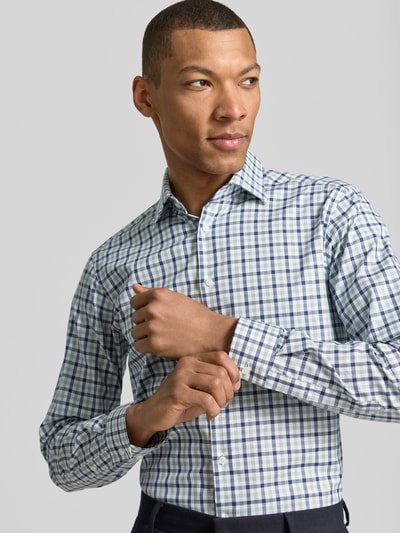 Męski model nosi Regular Fit Business-Hemd mit Kentkragen von Christian Berg Men, bawełna, krój regular fit, zapięcie na guziki, mankiety sportowe, zaokrąglony dół, długość pleców w rozmiarze 39/40: 78 cm, szerokość w rozmiarze 39/40: 47 cm, długość rękawa w rozmiarze 39/40: 65 cm, wzór w kratę, biel, granat i zieleń, całkowity widok z przodu