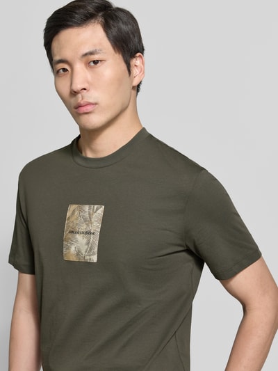 Männermodel trägt Regular Fit T-Shirt mit Logo-Patch von ARMANI EXCHANGE in Olivgrün, reine Baumwolle, Nahaufnahme Oberkörper.