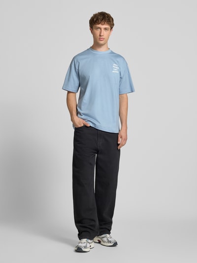 Männermodel trägt Loose Fit T-Shirt aus reiner Baumwolle Modell 'MONEY' von Only & Sons, Optik: Unifarben, Statement-Print, Jersey, Ganzkörperansicht von vorne.