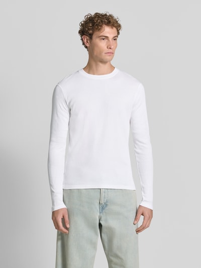 Männermodel trägt weißes Slim Fit Longsleeve aus reiner Baumwolle Modell 'Enil' von DRYKORN, Strukturmuster, Rundhalsausschnitt, Ganzkörperansicht von vorne.