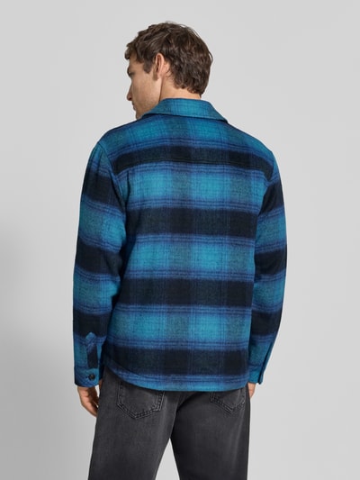 Männermodel trägt Regular Fit Hemdjacke mit Brusttaschen von Scotch & Soda im blauen Karomuster, Mix mit Woll-Anteil, Ganzkörperansicht Rückansicht.