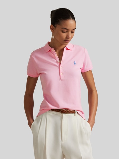 Kobiece model prezentuje Slim Fit Poloshirt aus Baumwoll-Mix von Polo Ralph Lauren, efekt: jednolity kolor, krój slim fit, wyhaftowane logo, kołnierzyk polo, listwa guzikowa, krótki rękaw, zakończenie z rozcięciem, pika, mieszanka bawełny, widok całej sylwetki z przodu.