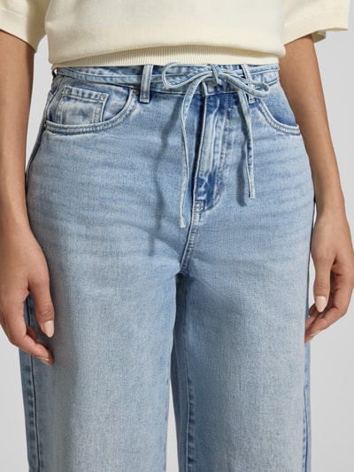 Frauenmodel trägt Loose Fit Jeans aus Baumwoll-Mix Modell 'WIEN' von Vero Moda in Denim-Optik mit Bindegürtel, 5-Pocket-Design, Nahaufnahme Oberkörper.