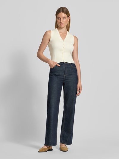 Frauenmodel trägt Strickweste aus Viskose-Mix mit V-Ausschnitt von Jake*s, Slim-Fit, Ripp-Optik, Knopfleiste, Rückenlänge 50 cm, Ganzkörperansicht von vorne.