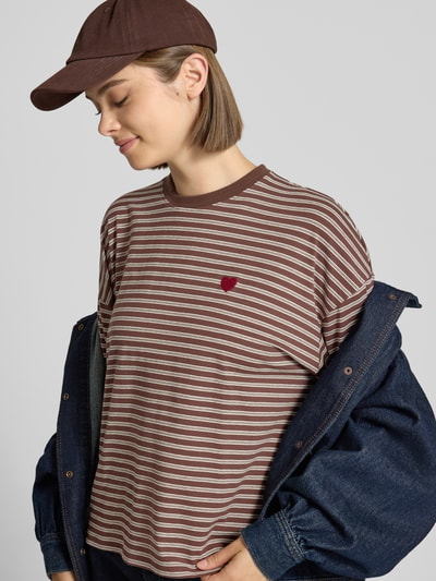 Kobiece model nosi brązowo-białą bluzę REVIEW Relaxed Fit Sweatshirt mit Baumwoll-Anteil z haftowanym logo, okrągły dekolt, długie rękawy, elastyczna mieszanka materiałów, długość tyłu w rozmiarze S: 52 cm, widok na górną część ciała z przodu.