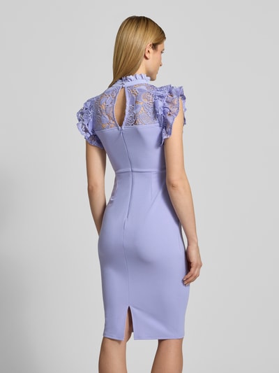 Modelka kobieca ma na sobie Slim Fit Midikleid mit Spitzenbesatz od Lipsy, elastyczna mieszanka materiałów, krój slim fit, obszycie koronką, stójka z obszyciem falbanami, krótkie rękawy z obszyciem falbanami, zamek błyskawiczny, półprzezroczysty materiał, zakładki, rozporek, długość tyłu w rozmiarze 36: 108 cm, szerokość w rozmiarze 36: 38 cm; widok całej sylwetki z tyłu.
