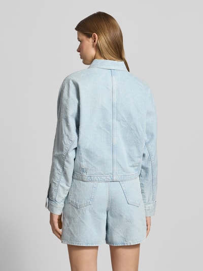 Frauenmodel trägt Jeansjacke mit Eingrifftaschen Modell 'DOLEMAN TRUCKER' von Calvin Klein Jeans, Reine Baumwolle, Gerader-Schnitt, Kentkragen, Knopfleiste, heller Denim-Look, feine Struktur, Ganzkörperansicht Rückansicht.