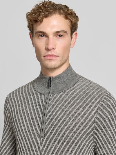 Männermodel trägt Regular Fit Strickpullover aus Schurwolle von Emporio Armani, grau mit Zickzackmuster, Troyer-Kragen, Nahaufnahme Oberkörper.