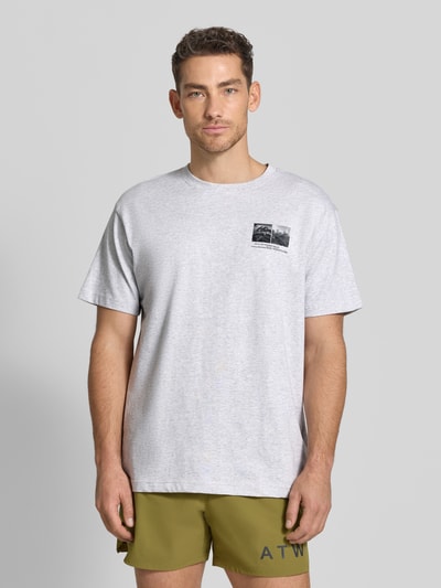 Männermodel trägt T-Shirt mit Motiv-Print und Rundhalsausschnitt von HALO aus reiner Baumwolle, regular Fit, graue Farbe, Ganzkörperansicht von vorne.