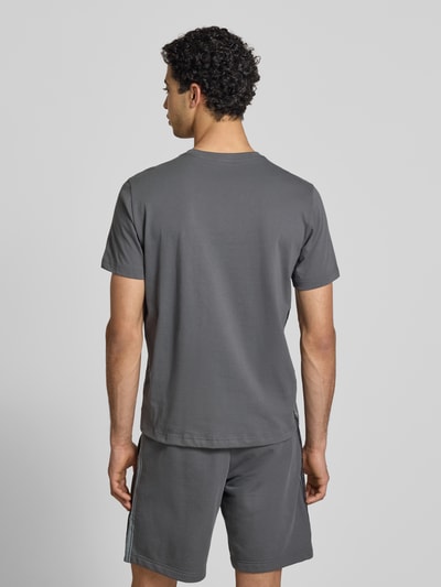 Männermodel trägt T-Shirt mit Logo und Rundhalsausschnitt von CHAMPION aus Reine Baumwolle, Regular-Fit, Rückenlänge 68 cm, Ganzkörperansicht Rückansicht.