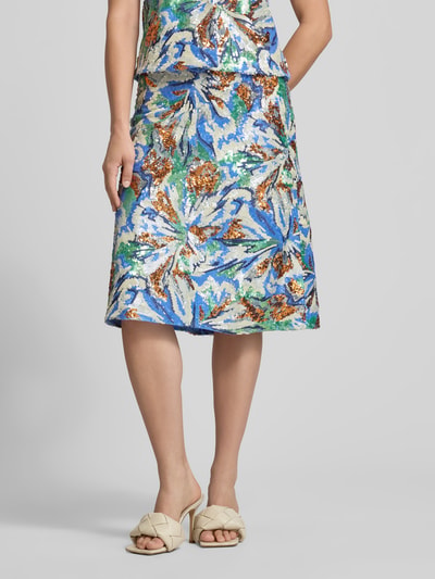 Frauenmodel trägt Midirock mit Allover-Pailettenbesatz von Rabanne, florales Design in Blau, Grün und Braun, leichte A-Linie, Nahaufnahme Unterkörper.