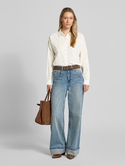 Modelka nosi Relaxed Fit Langarmbluse aus Baumwoll-Mix von Tom Tailor Denim, efekt: wzór w grochy na całej powierzchni, krój relaxed fit, kołnierzyk koszulowy, detale z efektownej przędzy, pas na plecach z marszczeniem, listwa guzikowa, długi rękaw z mankietami, wykończenie lekko zaokrąglone, mieszanka bawełny, jasna tonacja, gładka tekstura, całkowity widok z przodu.