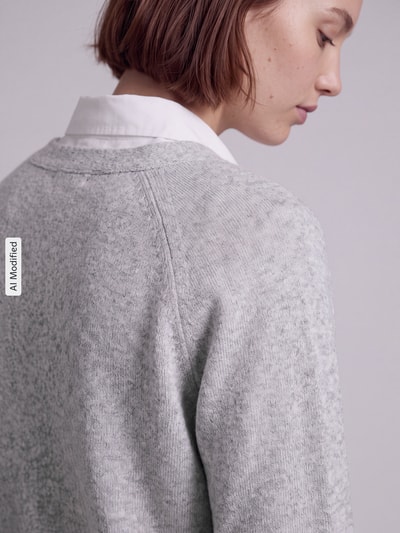 Frauenmodel trägt hellgraue Oversized Strickjacke mit Woll-Anteil Modell 'BOOM' von VERO MODA, Damen Strickjacke, Nahaufnahme Oberkörper, KI-modifiziertes Bild