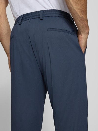 Männermodel trägt Regular Fit Hose mit Tunnelzug und Eingrifftaschen von bugatti in Dunkelblau, Material-Mix, Nahaufnahme Rückansicht.