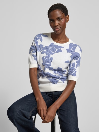 Frauenmodel trägt Strickpullover im Allover-Look mit 1/2-Arm von Christian Berg Woman aus Material-Mix mit Viskose-Anteil, Slim-Fit, Rundhalsausschnitt, weiße Grundfarbe mit blauen Blumen, weiche texturierte Struktur, Ganzkörperansicht von vorne.